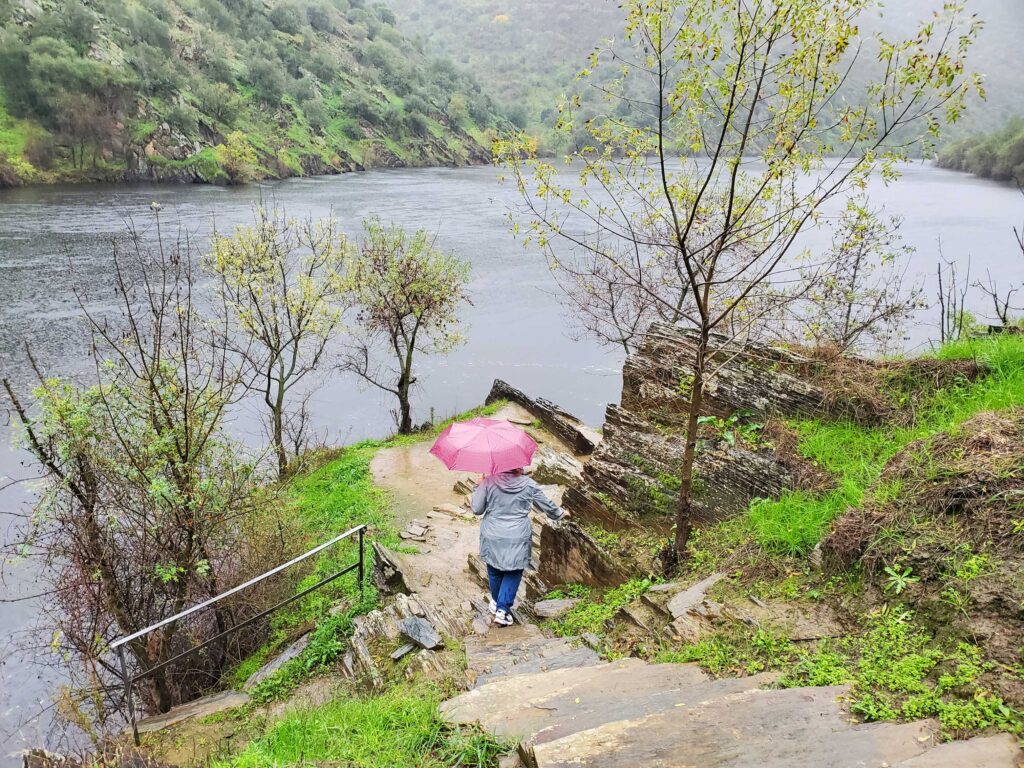 Andrea carefully navigating the stone stairs in the rain at an archeological site near Vila Nova de Foz Côa, Portugal